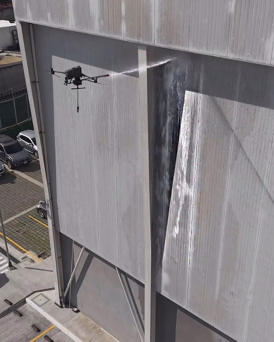 Dron de VERTIKA lanzando el chorro de lavado sobre la fachada de una galera industrial